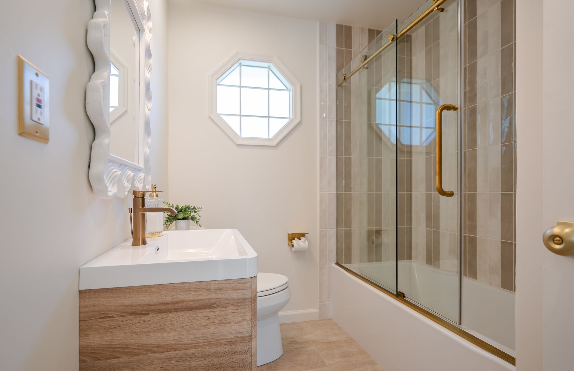 Bright bathroom with white walls, wood vanity, octagonal window, and glass shower enclosure.