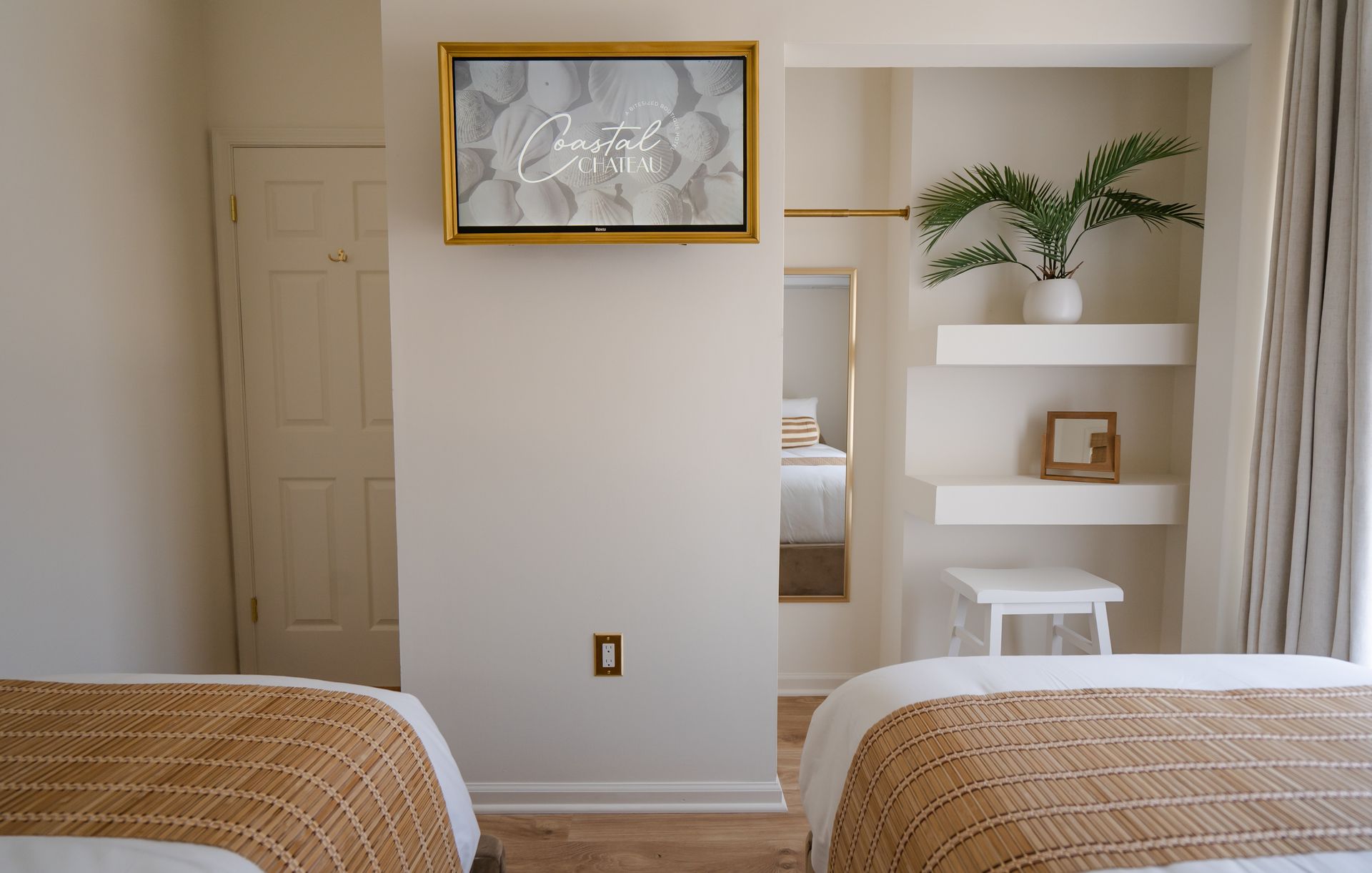 Cozy bedroom with twin beds, white desk nook, plant shelves, and abstract wall art.