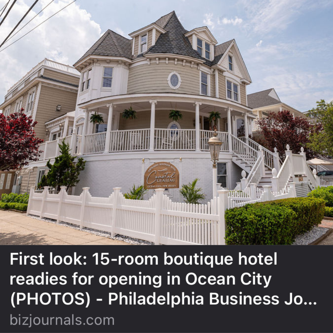 Exterior of a Victorian-style boutique hotel in Ocean City, with a white picket fence and a sign.