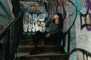 A woman is sitting on a set of stairs with graffiti on the wall.
