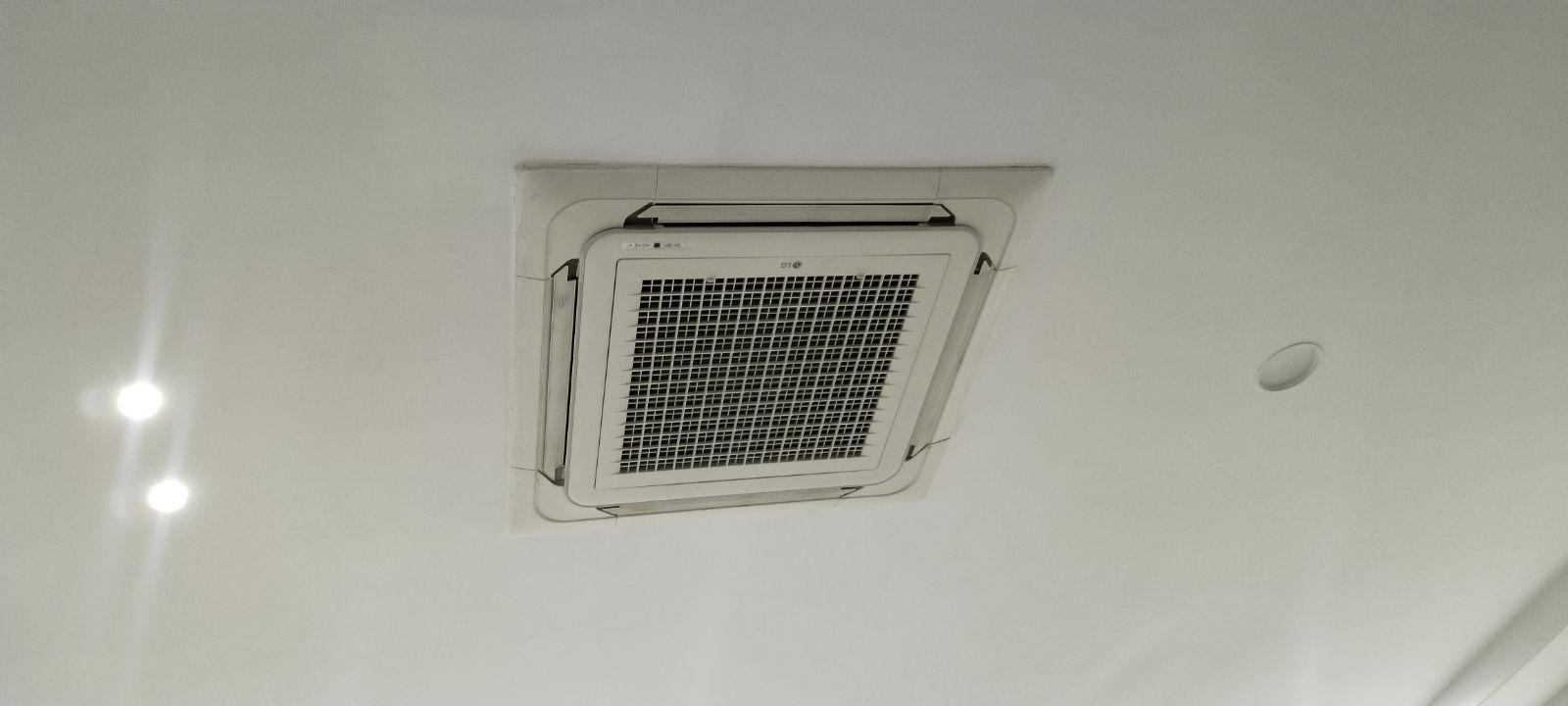 White ceiling with a square air vent and a small round sensor nearby