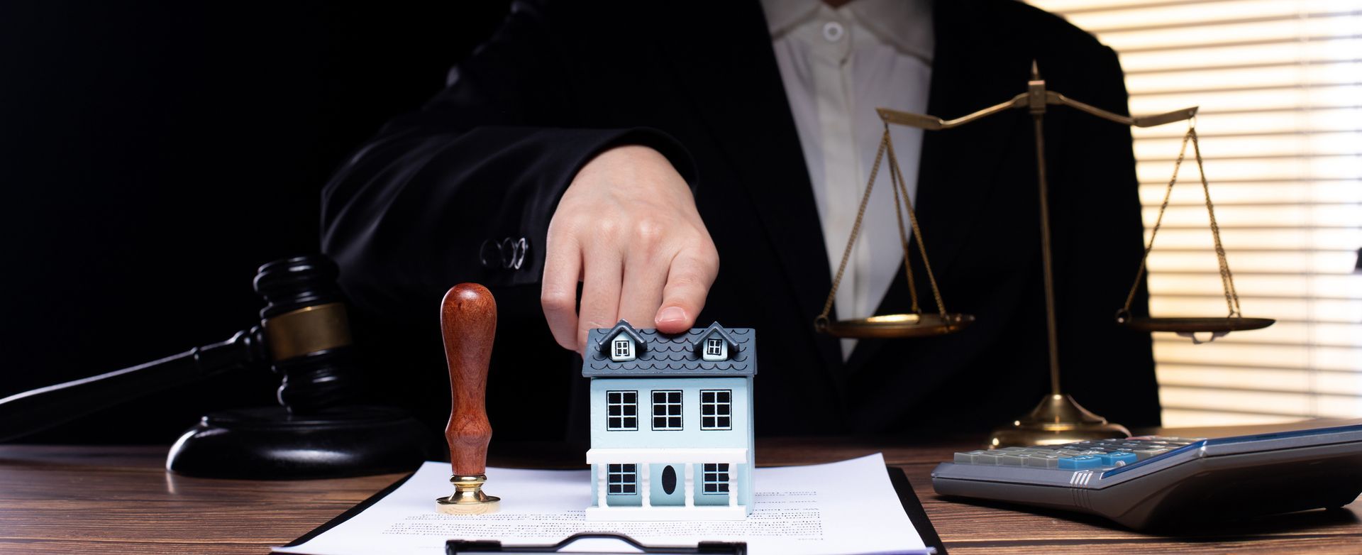 Hand placing a model house on a document with gavel - Conveyancing Solicitor in Canberra