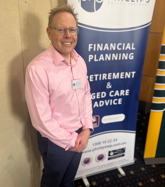 Man in pink shirt smiles, stands by banner for financial planning, retirement, and aged care advice.