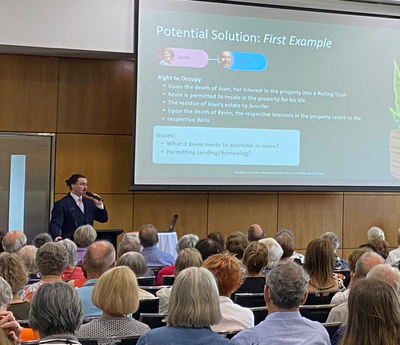 Man presenting to a crowd, with a slide titled 