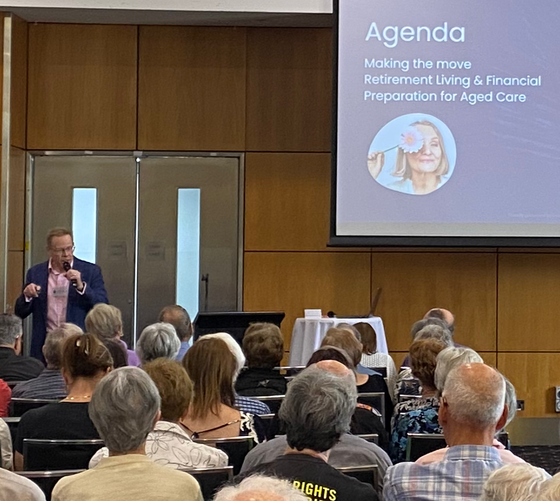 Man speaking at a presentation about retirement and aged care to an audience.