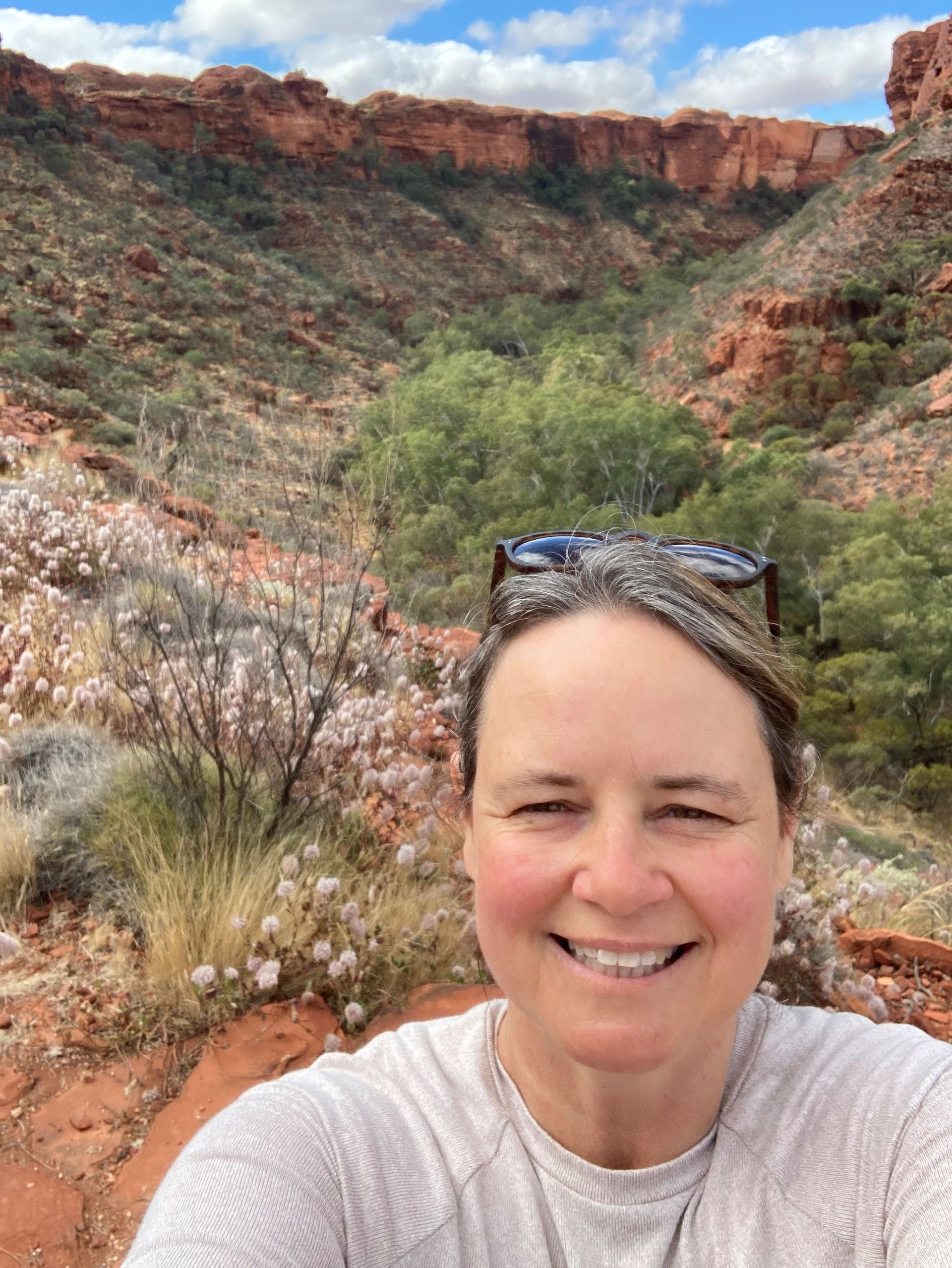 Woman smiling at the camera with a canyon landscape backdrop.