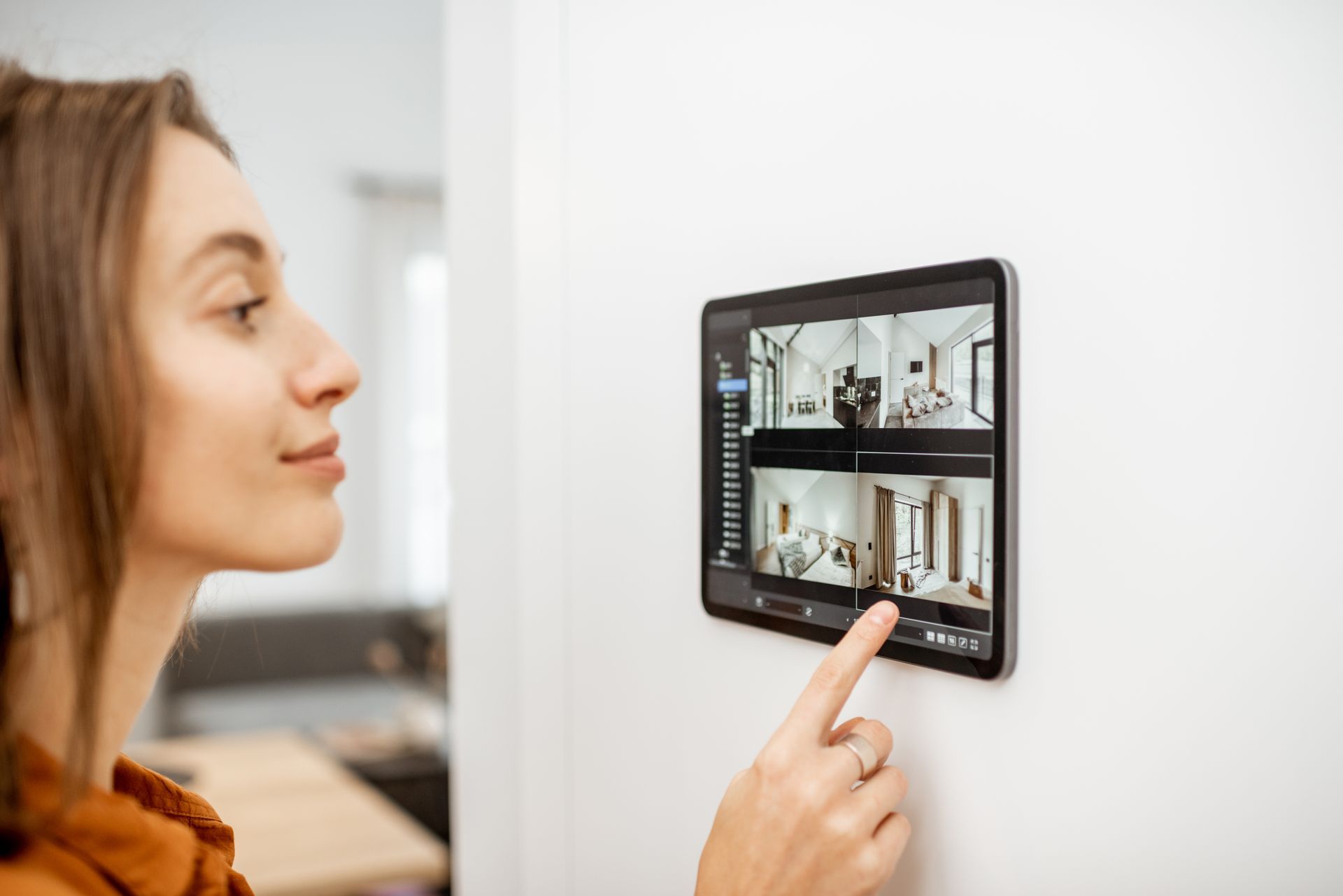 Young woman watching video from security cameras on a digital tablet at home. Young woman watching video from security cameras on a digital tablet at home.