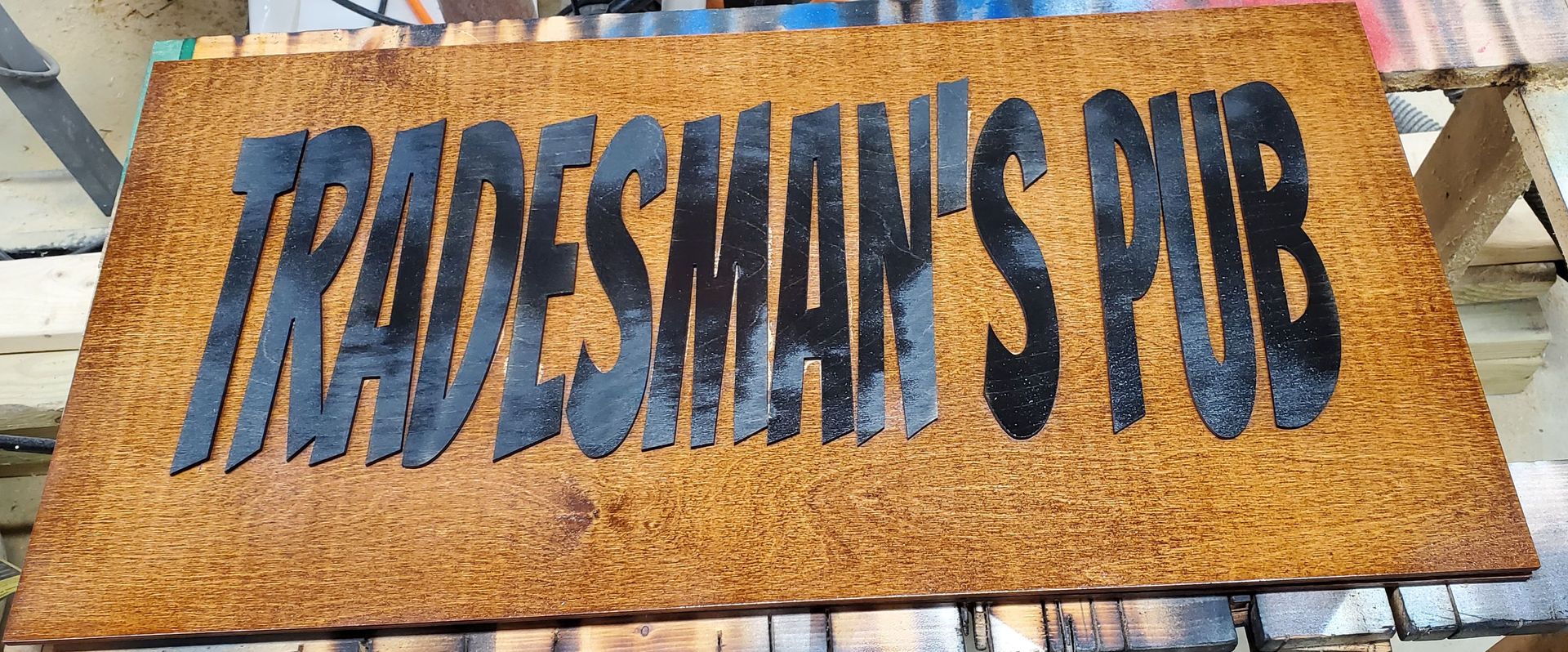 “Tobesman's Pub” sign on a rustic wooden board with blue lettering