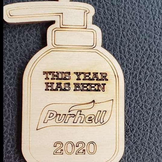 Wooden bottle-shaped plaque reading “THIS YEAR HAS BEEN Purcell 2020” on a dark textured background