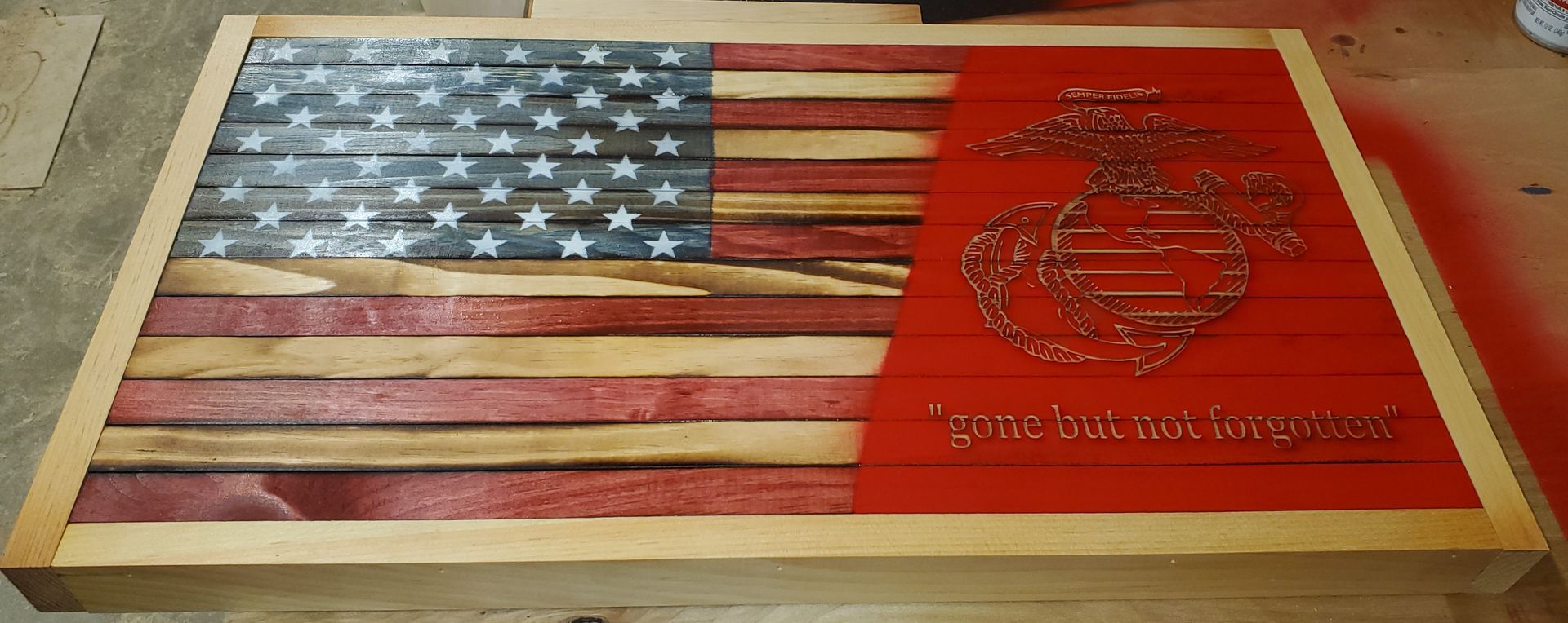 U.S. flag with a red panel featuring the Marine Corps emblem and text on a wooden plaque