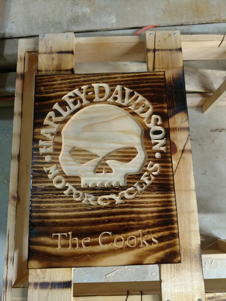 Wooden Harley-Davidson skull logo sign with “The Cooks” engraved beneath it.