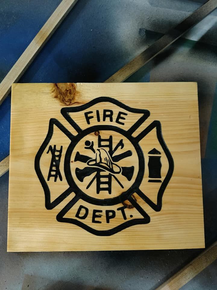 Wooden plaque with a black fire department emblem on a blue background