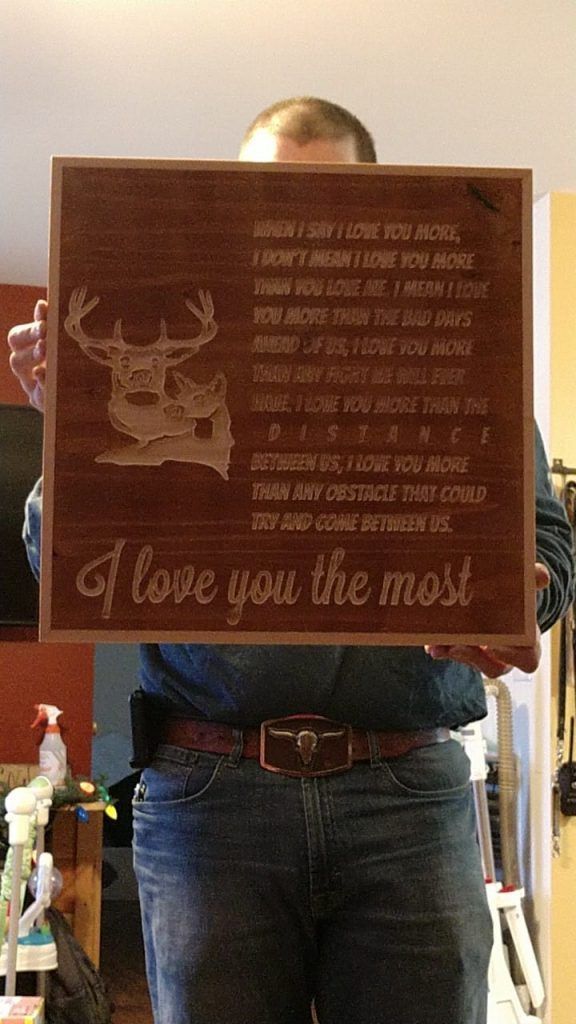 Person holding a brown plaque with a deer and the words “I love you the most”
