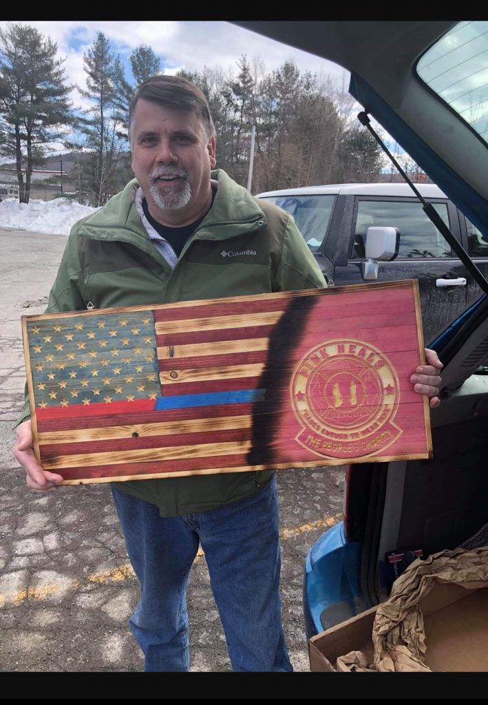 Person holding a weathered American flag with a red seal in a snowy outdoor setting