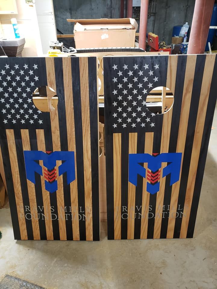 Two striped cornhole boards with stars and blue logos on a workshop floor