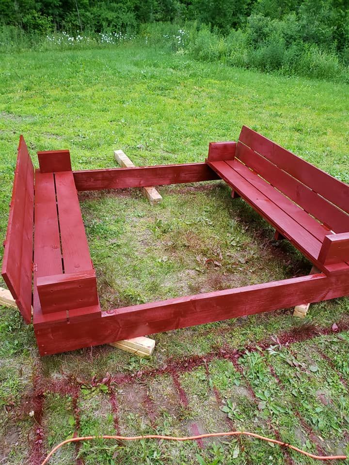 Red wooden raised platform frame on grass in a green yard
