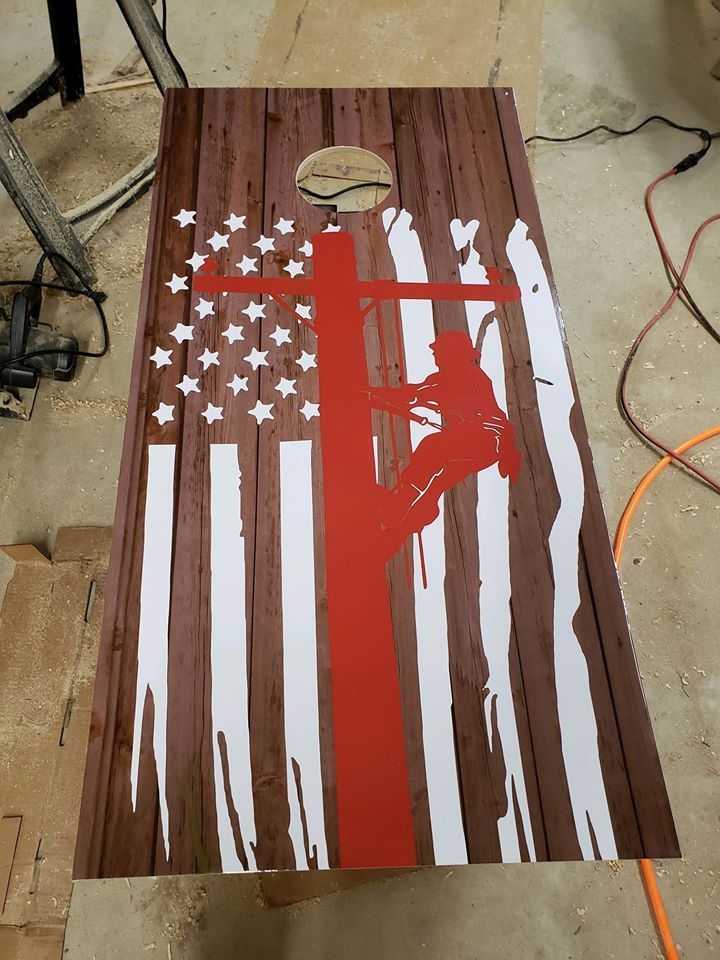 Painted wooden board with a distressed American flag and red silhouette figure in a workshop.