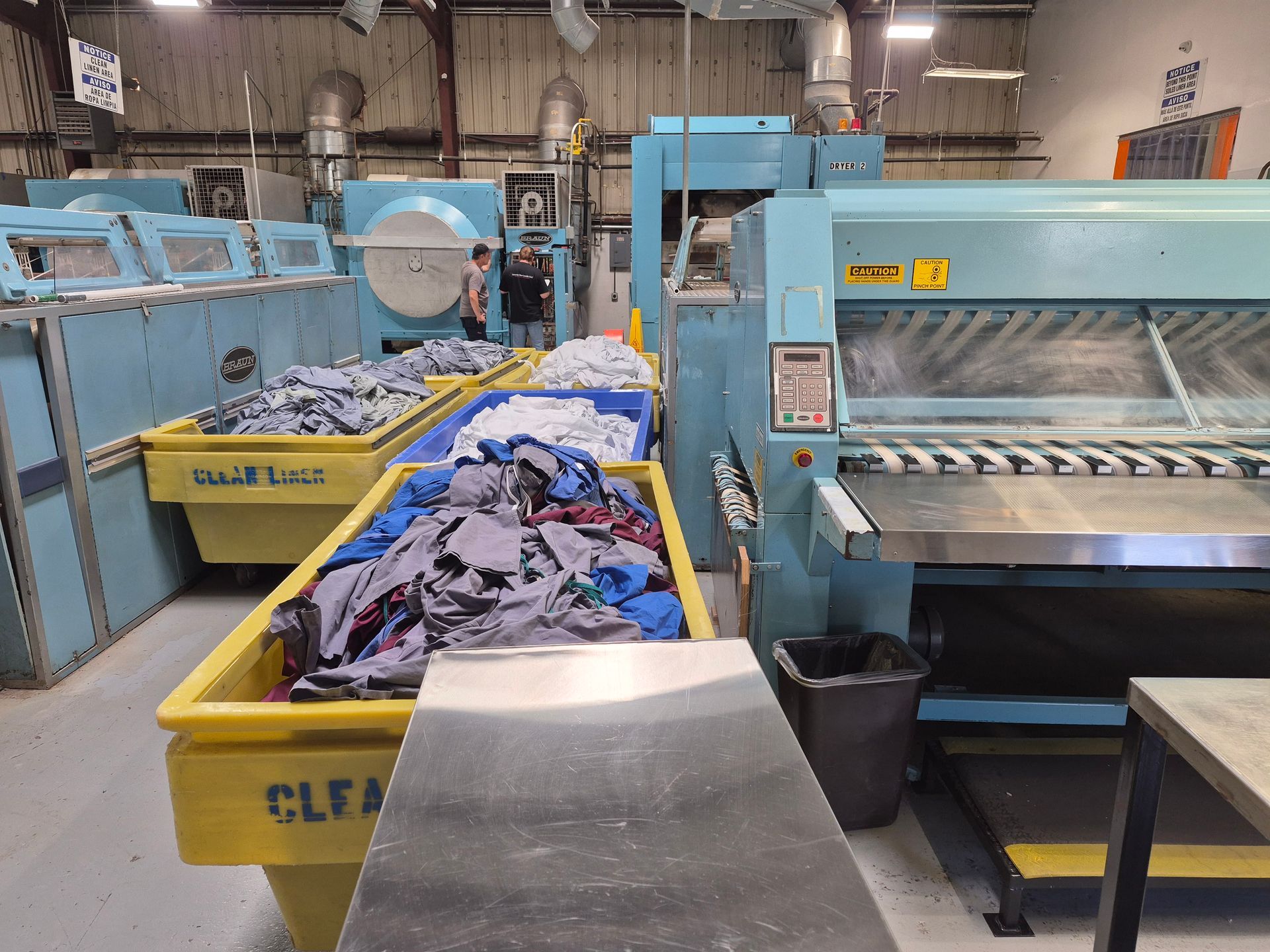 Laundry machines and bins filled with clothes inside an industrial laundry facility.