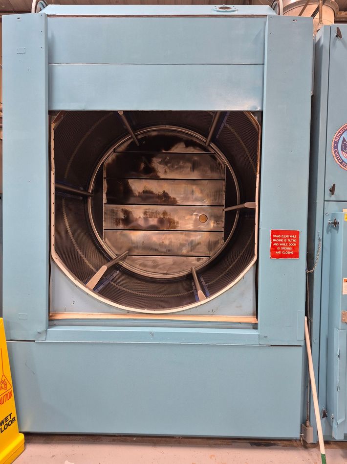 Large, blue industrial air handler with fan and vents. Warning sign on the right side.