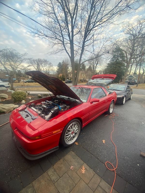A red sports car with the hood up is parked in a driveway. | Compassion Auto Care LLC