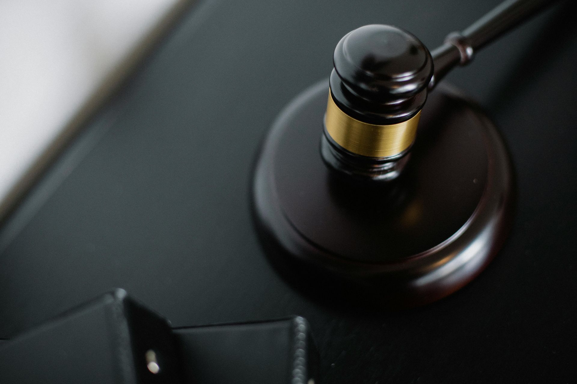 Gavel on a wooden block, angled, top down view on a dark surface.