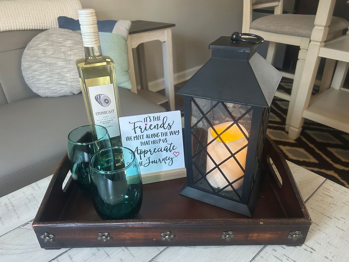 A tray with a bottle of wine glasses and a candle on it