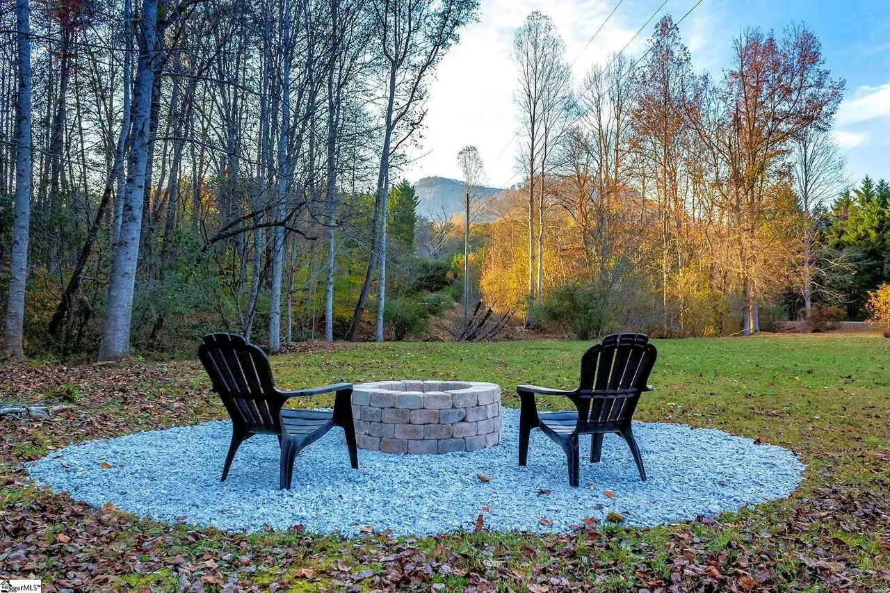 Two chairs are sitting around a fire pit in the middle of a field.