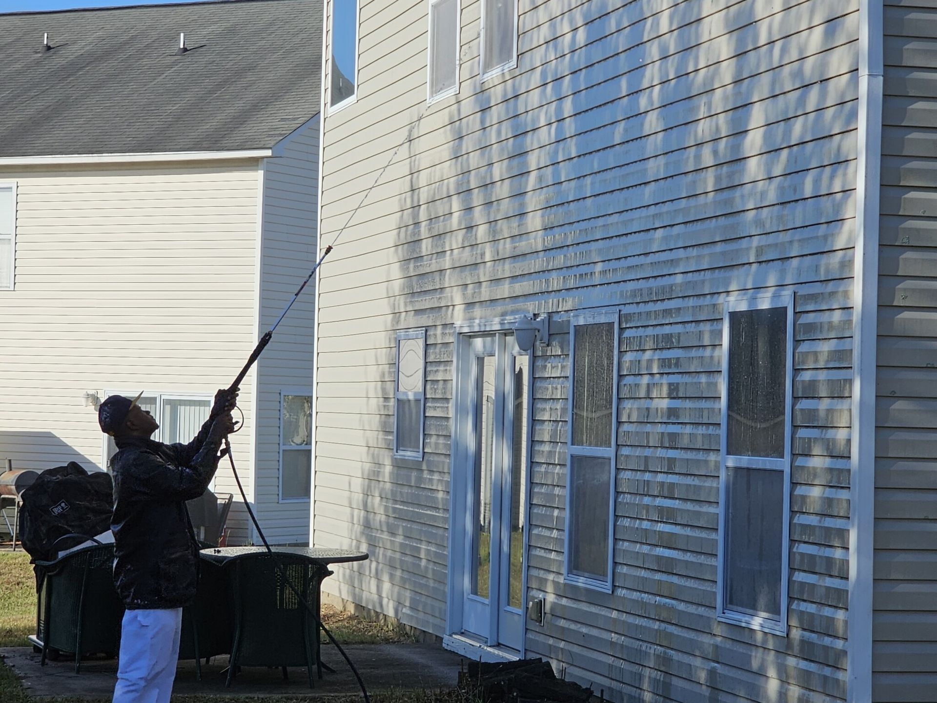Pressure washing a wooden fence, revealing bright wood.