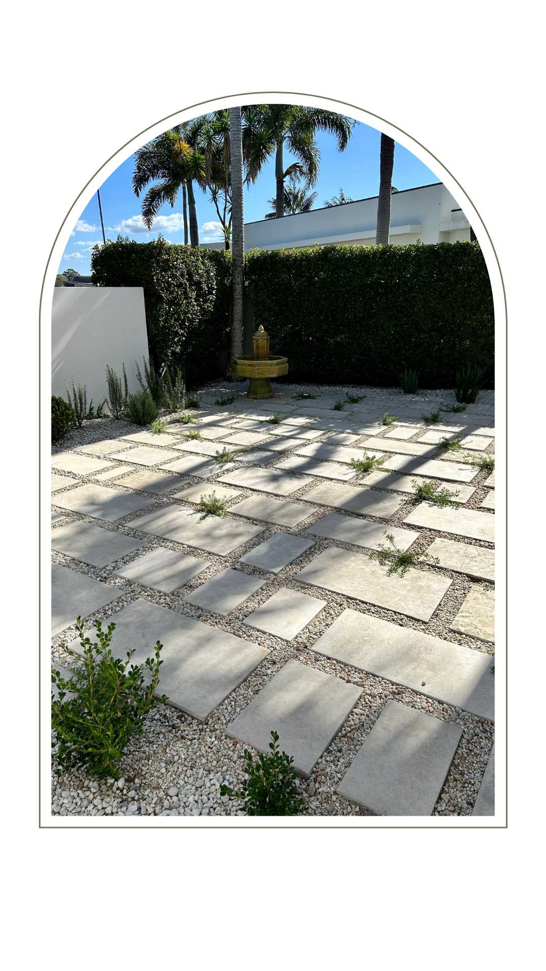 A garden patio features square stone pavers arranged in a grid, separated by gravel, with a small fountain in the back.