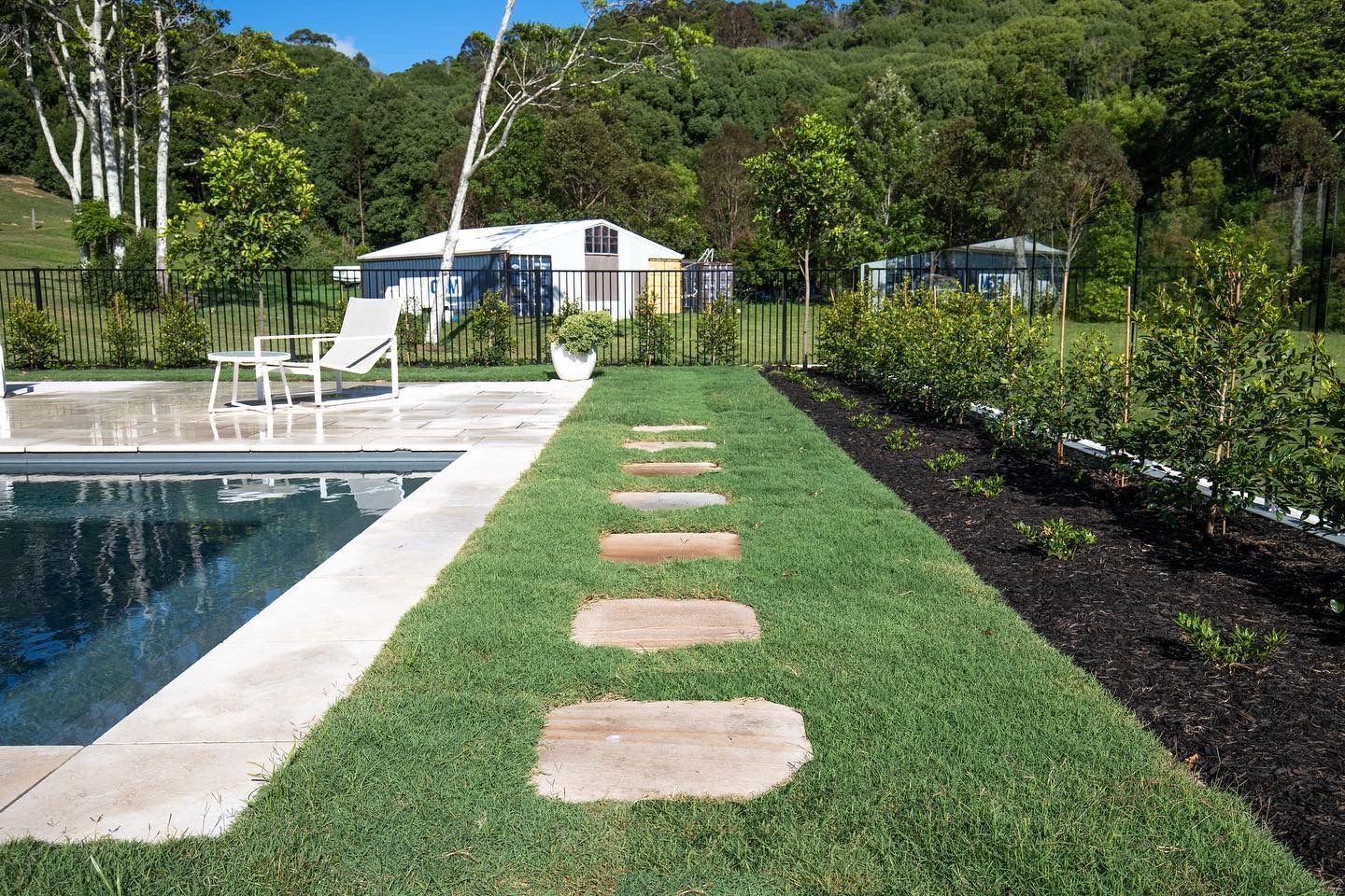 a fence surrounds a swimming pool with a shed in the background