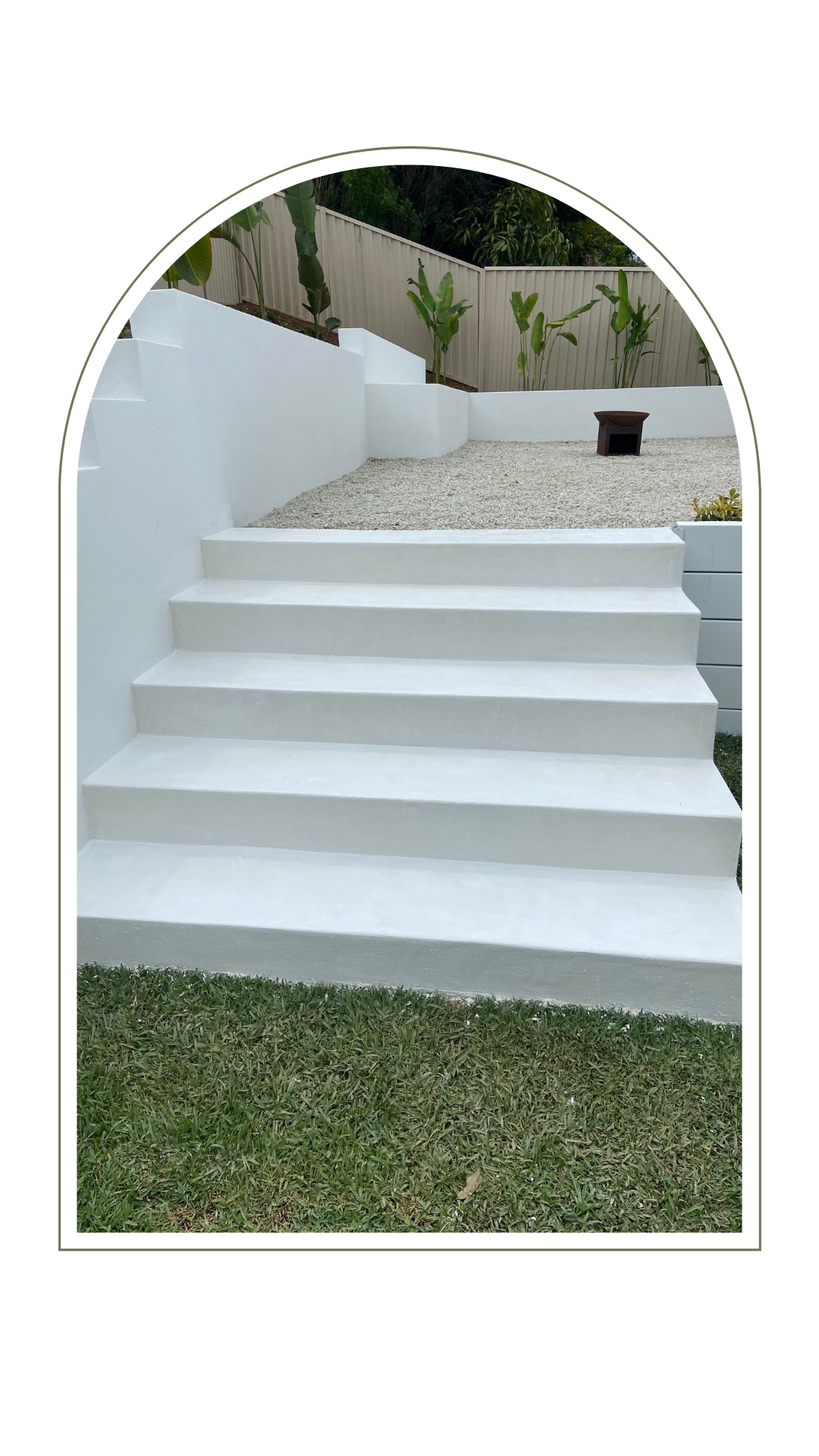 A white outdoor staircase leading up to a gravel patio with low white walls and small plants, framed in an arch.
