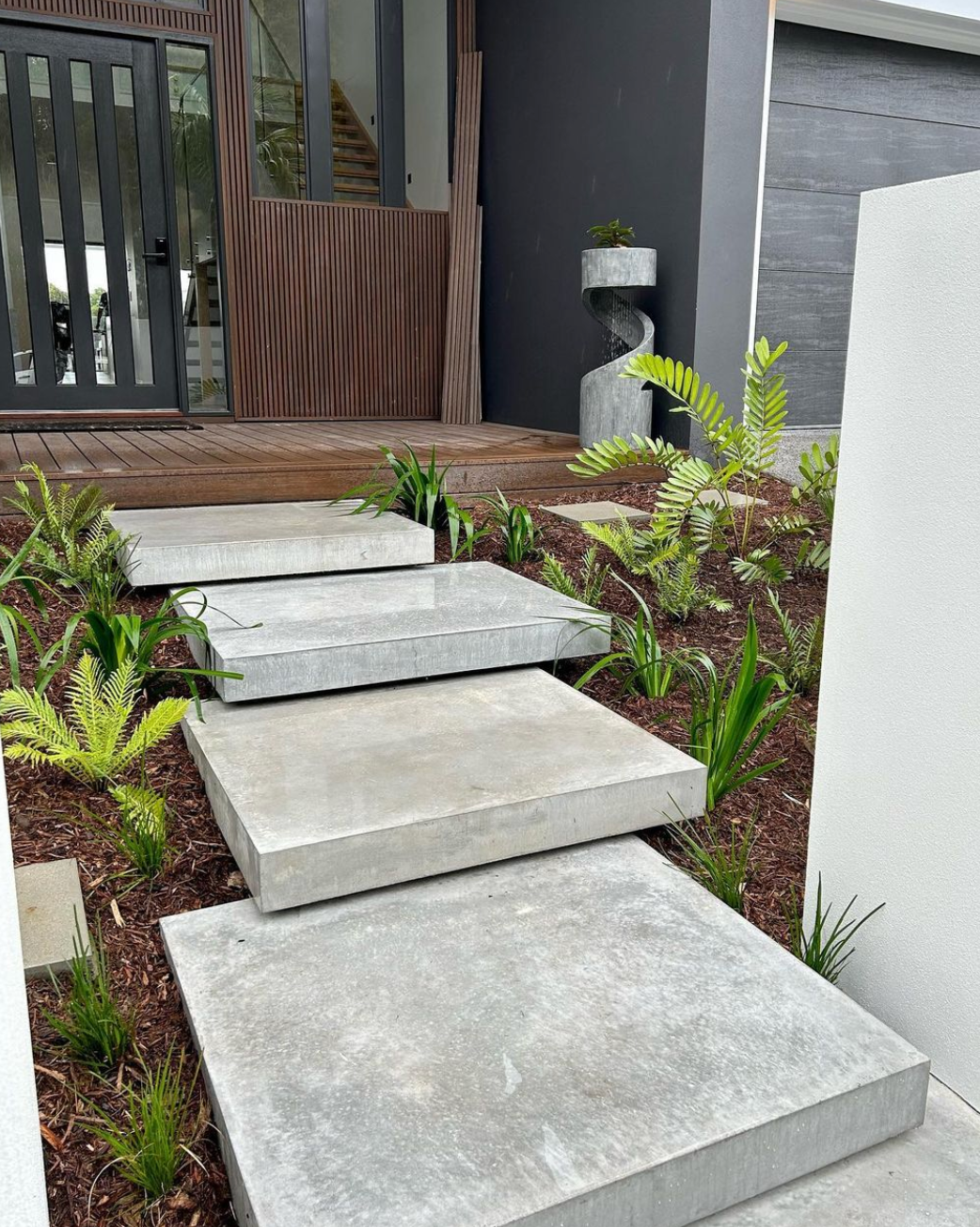 a floating concrete walkway leads to the front door of a house