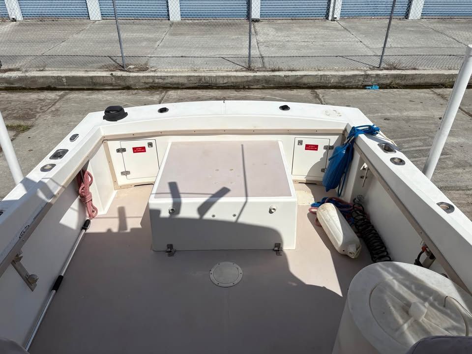 Empty boat cockpit with white benches, gray deck, and a dock visible ahead.
