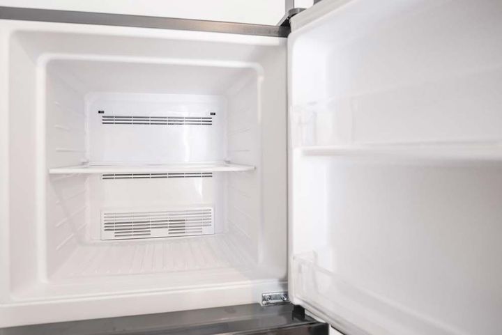Empty white refrigerator interior with adjustable shelves and open door, showing clean cooling vents. Empty white refrigerator interior with adjustable shelves and open door, showing clean cooling vents.