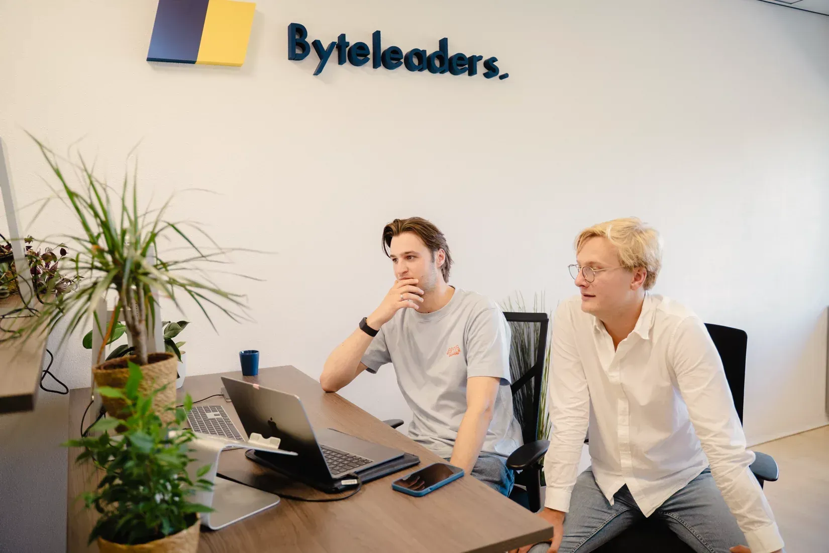 Een man zit aan een bureau en kijkt naar een computerscherm.