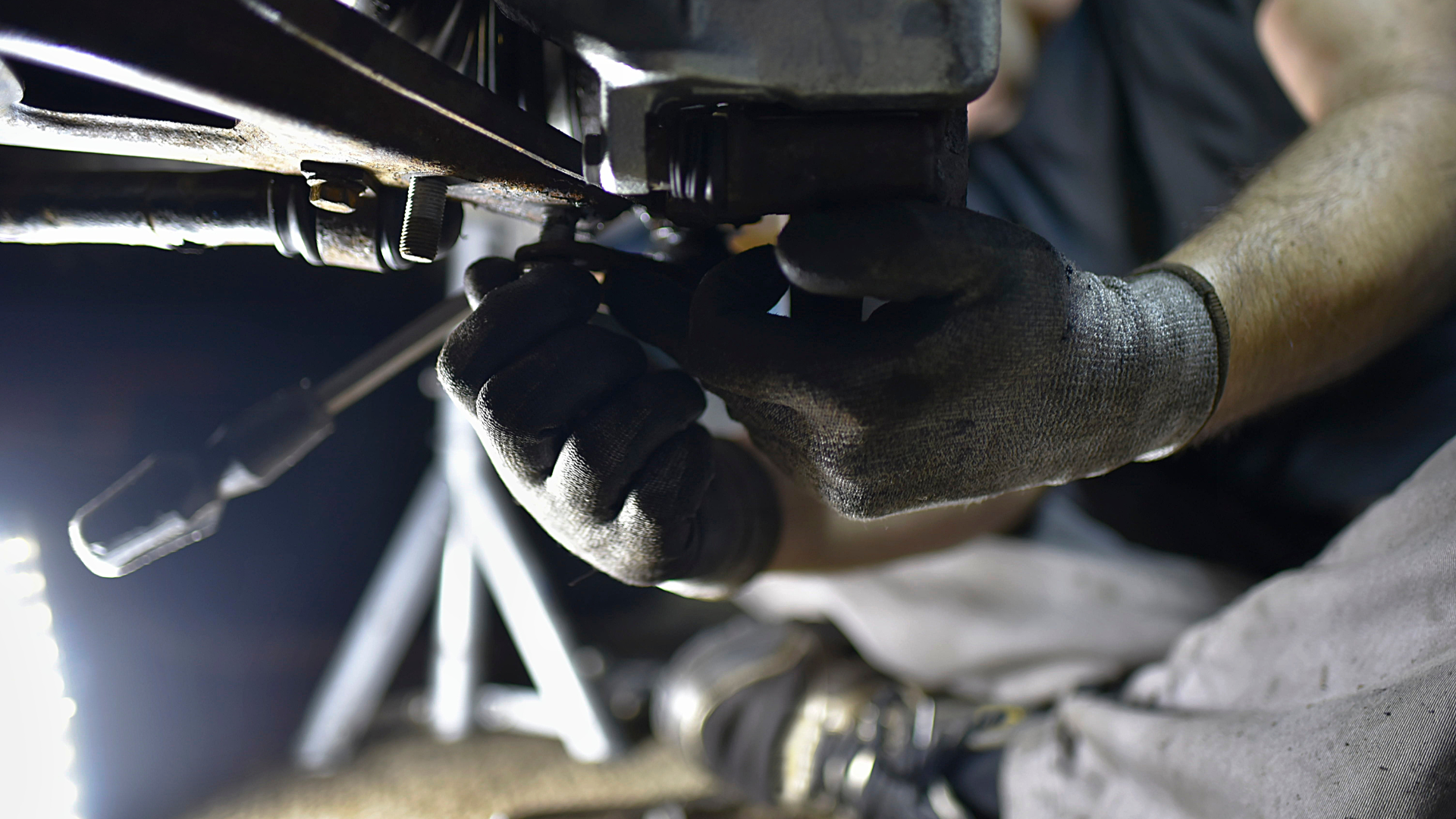 A man wearing gloves is working on a piece of metal.