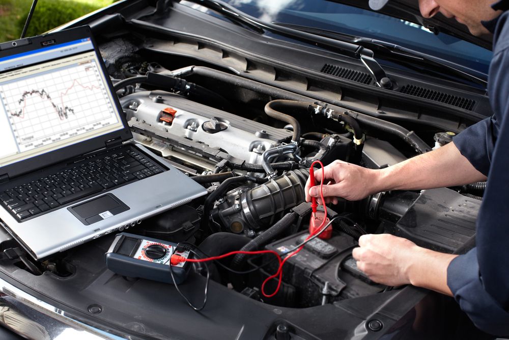A Man Is Writing on A Clipboard in Front of A Truck Engine — Modern Motors-Nabiac in Nabiac, NSW