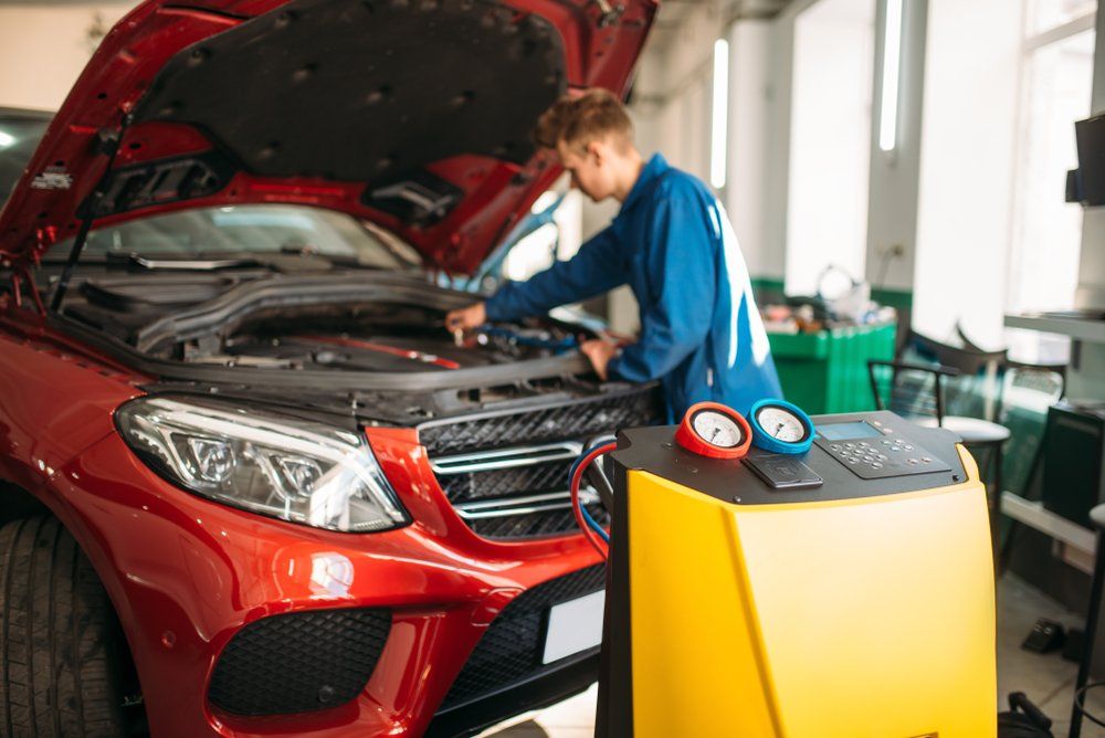 A Man Is Working on The Engine of A Red Car in A Garage — Modern Motors-Nabiac in Nabiac, NSW