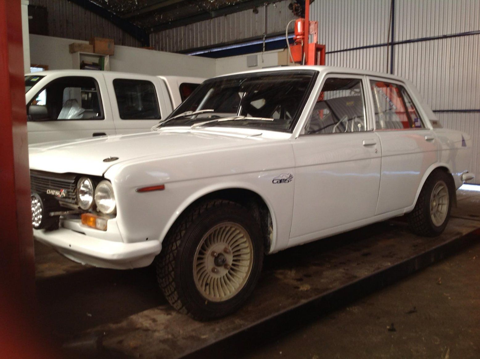 A White Car Is Parked in A Garage Next to A White Truck — Modern Motors-Nabiac in Nabiac, NSW