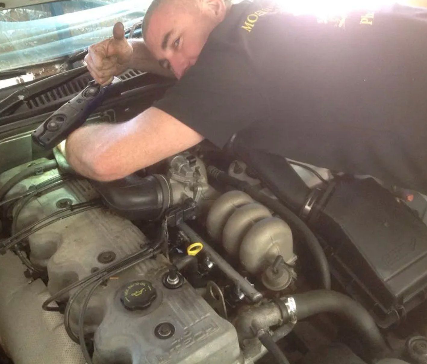 A Man in A Black Shirt Is Working on The Engine of A Car — Modern Motors-Nabiac in Nabiac, NSW