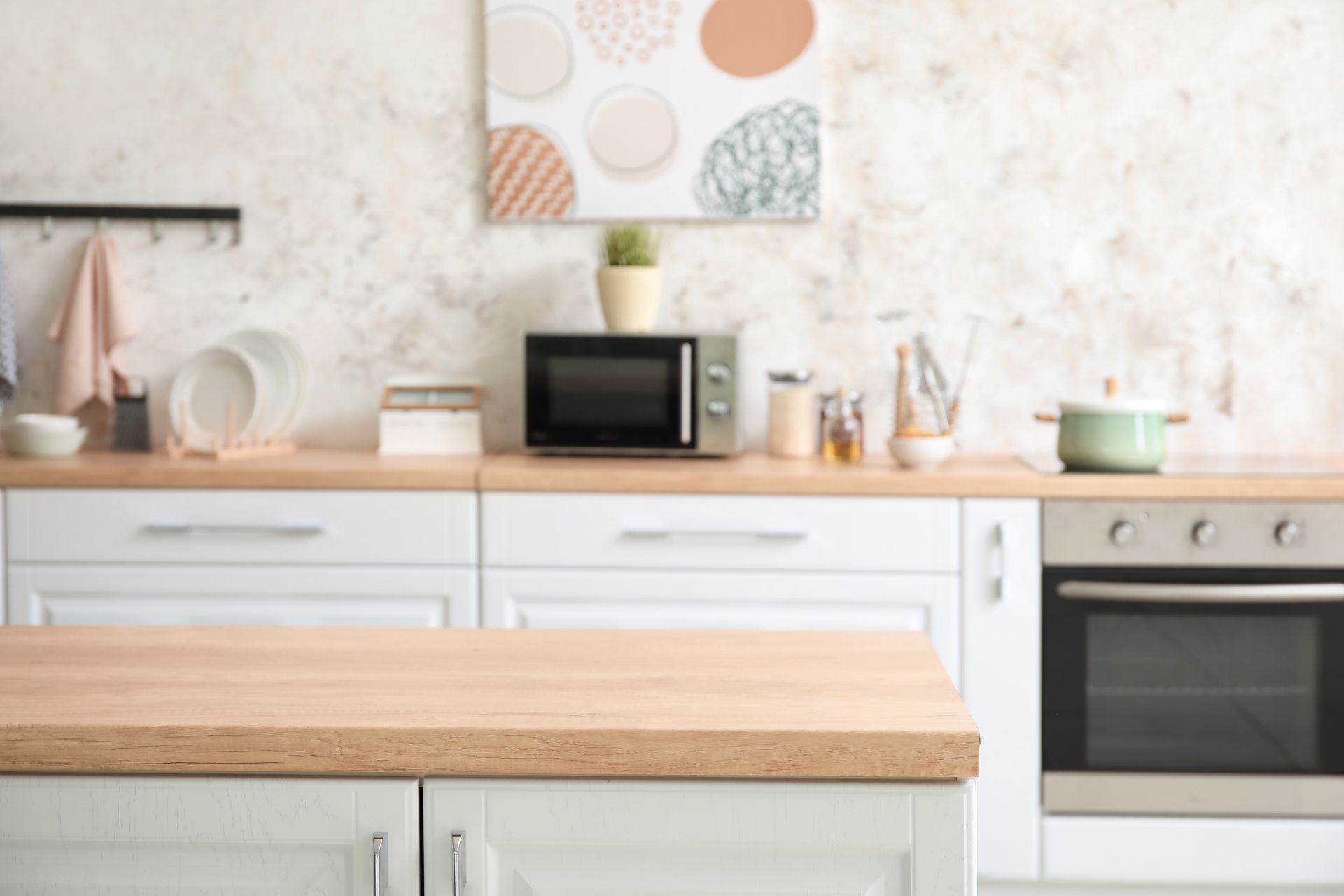 White kitchen with wooden countertops, microwave, and oven.
