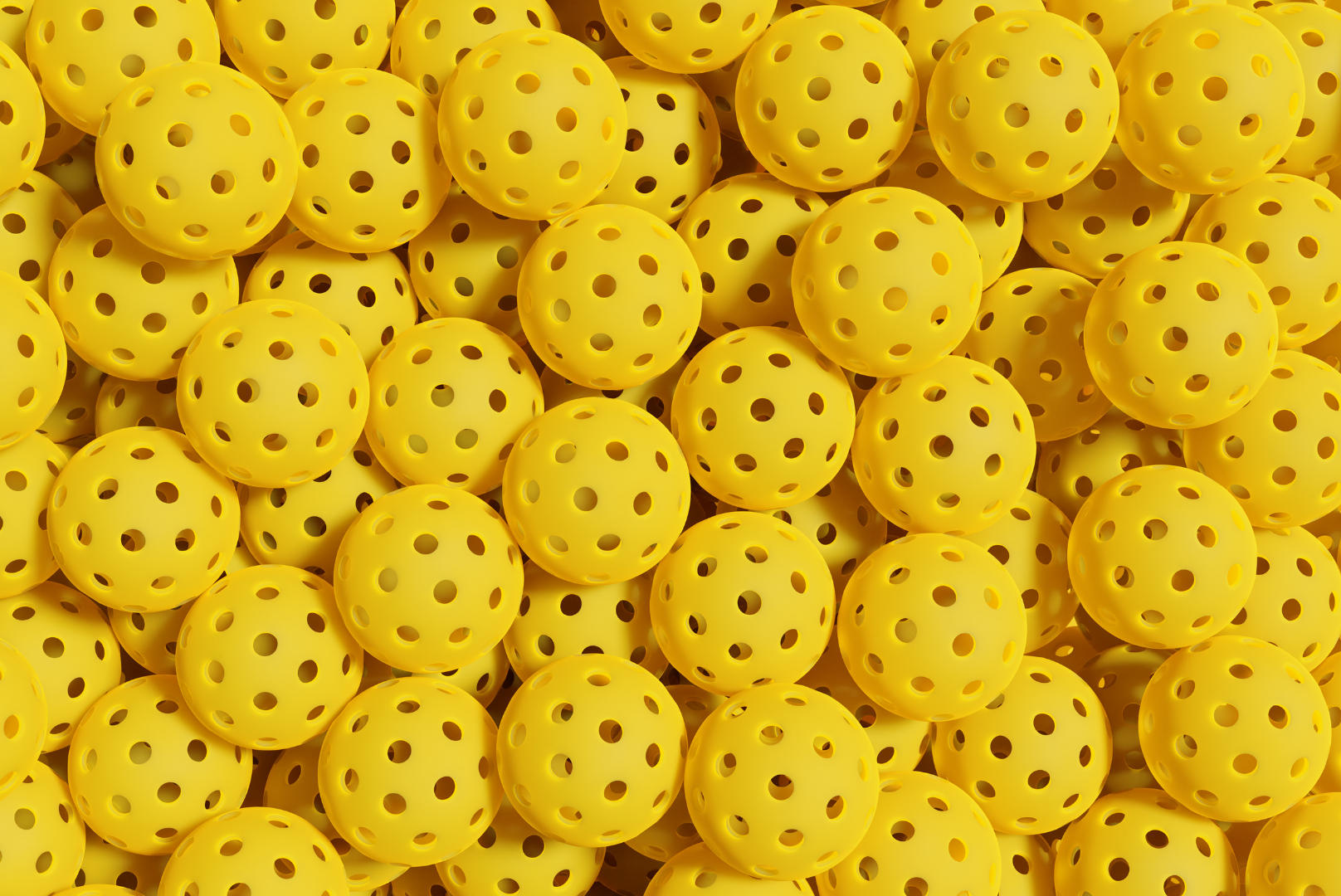 Pile of bright yellow perforated plastic balls filling the frame