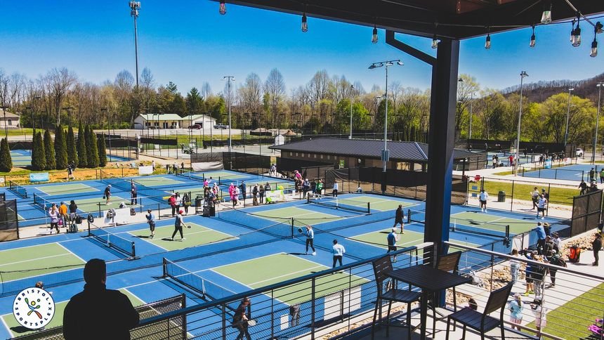Register Today! Outdoor pickleball courts at Bristol Sportsplex, with many players practicing under a clear blue sky, viewed from the VIP Reception Area.