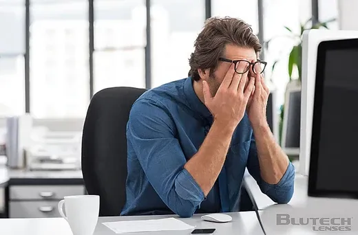 man rubbing his eyes sitting at his desk