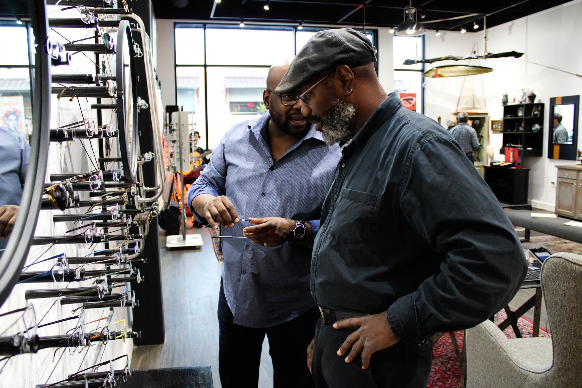 Optician Dominic helping a client find fashionable frames, interior CustomEyes shop