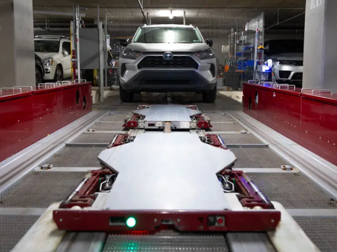 A car is sitting on a conveyor belt in a parking garage.