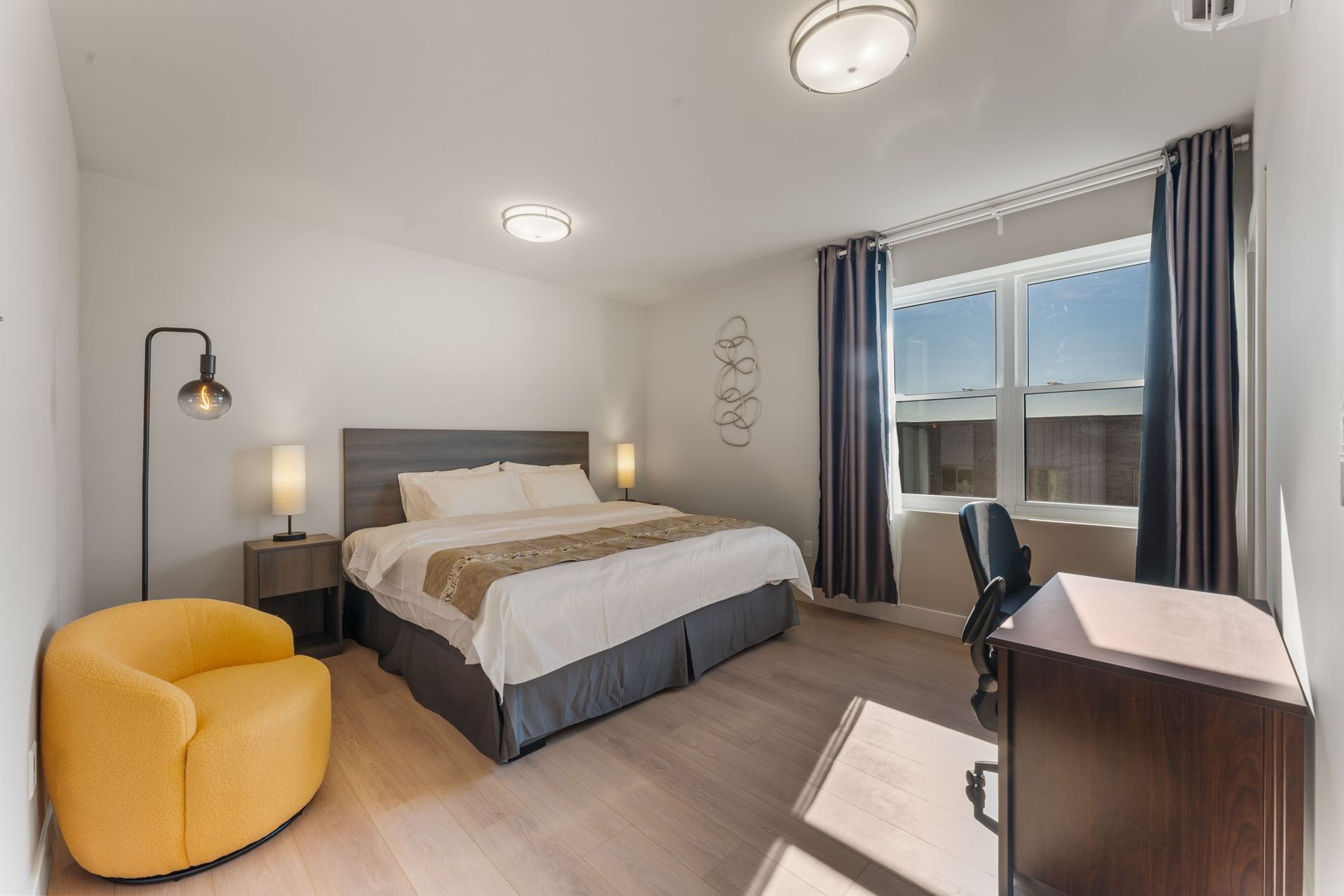 A bedroom with a bed , chair , desk and window.