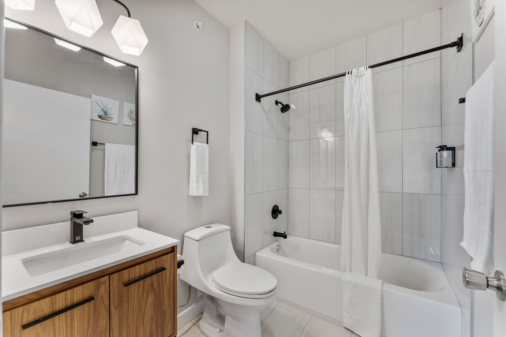 A bathroom with a toilet , sink , tub and mirror.