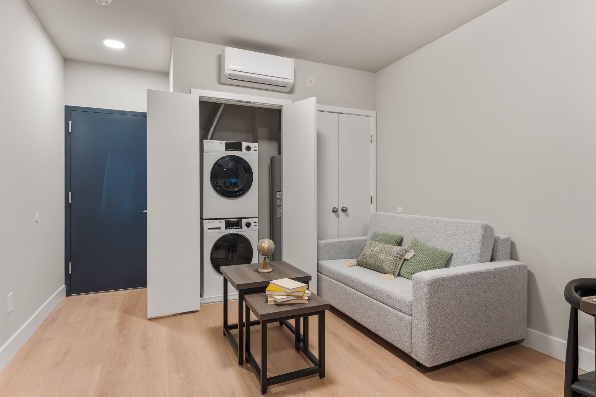 A living room with a couch and a washer and dryer stacked on top of each other.