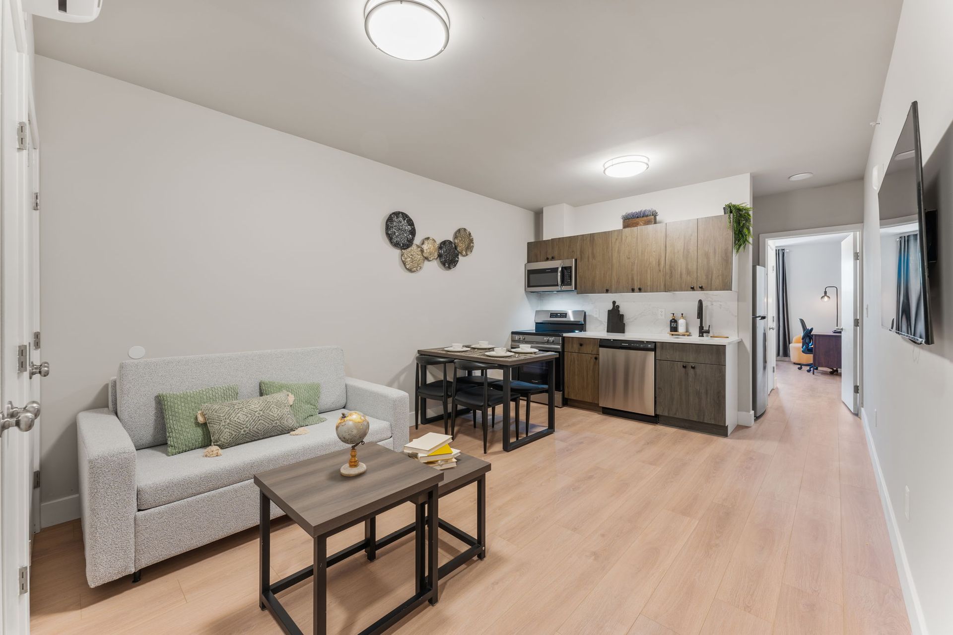 A living room with a couch , table , chairs and a kitchen.